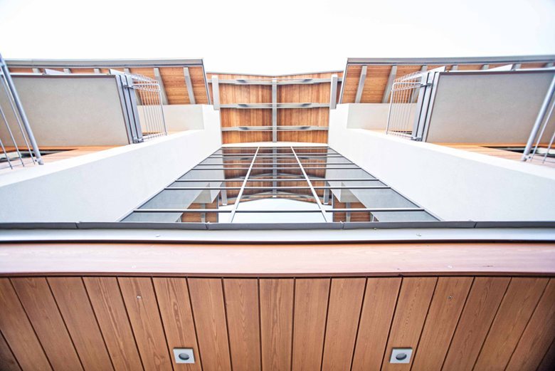 Edificio multipiano in X-Lam visto dal basso, con i balconi e l'intradosso in legno, Betulle, Nole