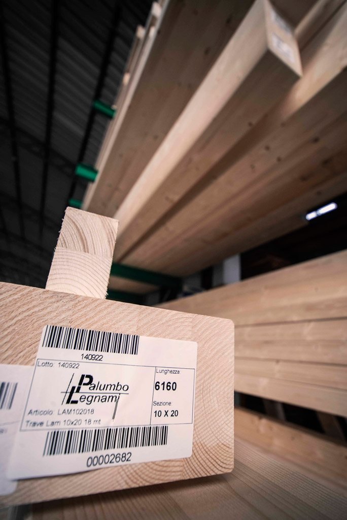 Trave in legno lamellare 10×20 con l’etichetta Palumbo Legnami, sulle rastrelliere del magazzino